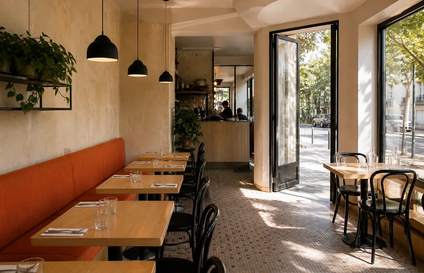 Vue d’ensemble du restaurant avec sa banquette corail, son comptoir et la porte ouverte sur la rue.